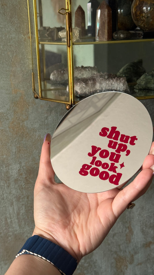 Flexibel rond spiegeltje 12,5 cm met rode tekst ‘Shut up, you look good’, ophangbaar en neerzetbaar voor wanddecoratie.