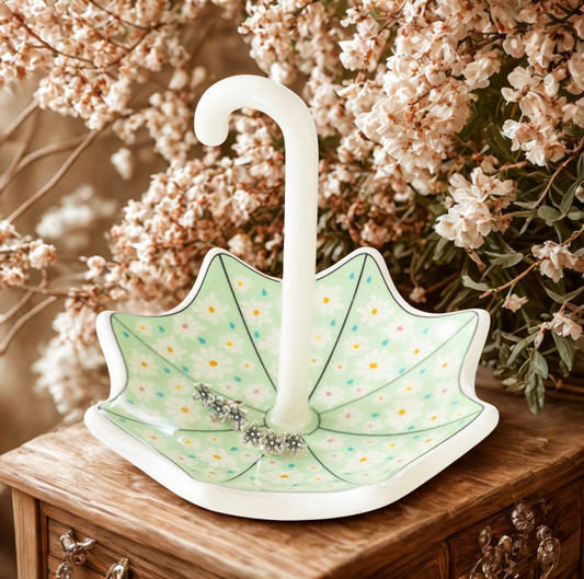 Een charmant keramieken sieradenbakje in de vorm van een paraplu met een delicate bloemenprint, gepresenteerd in een licht en fris voorjaarsinterieur.