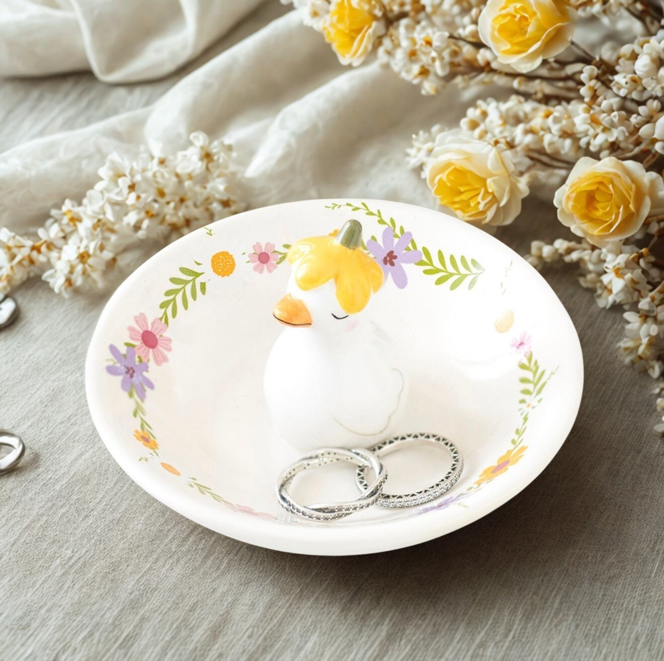 Een schattig keramieken sieradenschaaltje met een eendje in een bloemenhoedje, perfect voor het bewaren van ringen en oorbellen.